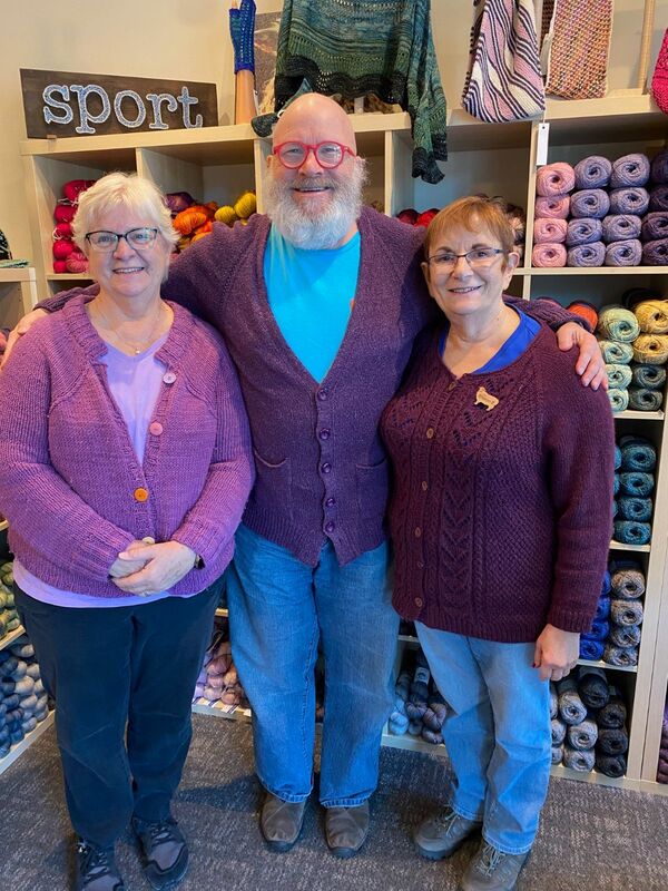 3 people wearing knit cardigans in shades of purple