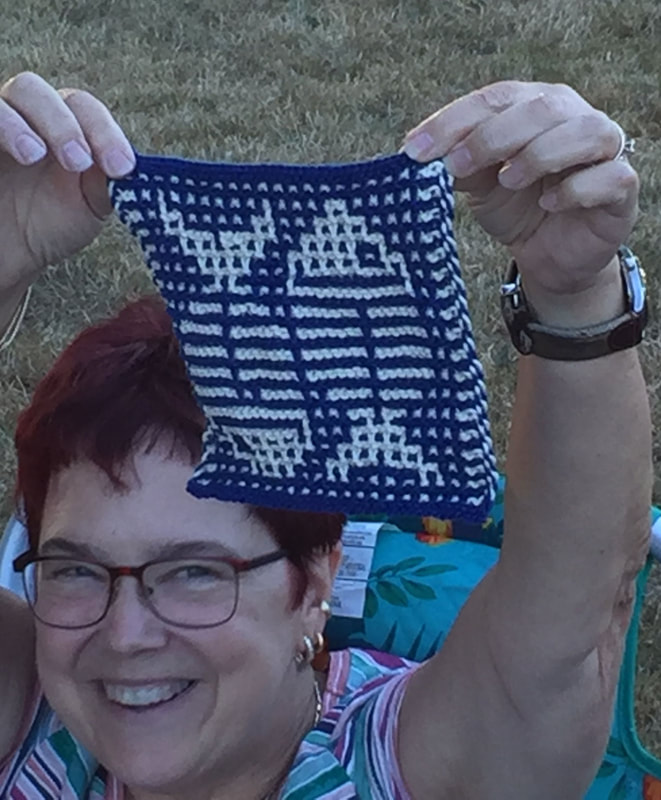 Woman holding up a blue and white patterned wash cloth with a fish design